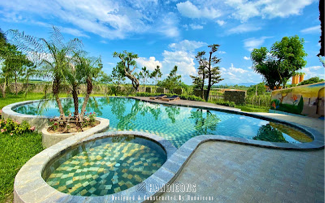 Hồ bơi ngoài trời hình bán nguyệt của Nana House Villa, bao quanh bởi cảnh quan sân vườn xanh mát.