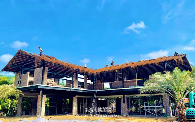 Thi công lắp dựng khung thép tiền chế và lợp mái lá truyền thống cho biệt thự nghỉ dưỡng sinh thái.