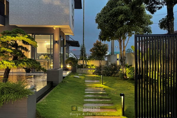 Lối đi sân vườn được lát đá trên nền cỏ, dẫn dắt từ cổng vào sâu trong khuôn viên.