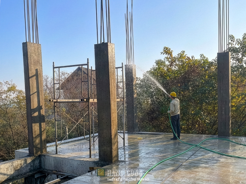 Kỹ sư tưới nước bảo dưỡng cột bê tông sau khi tháo cốp pha tại công trường Hanoicons, giúp kết cấu nhà đẹp luôn bền vững.